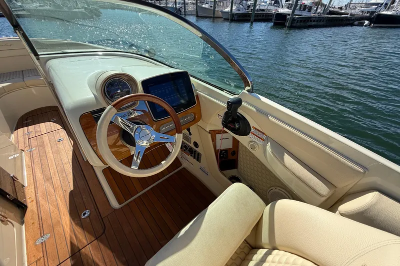 Slide: The Image of 2019 Chris-Craft Launch 28 GT cockpit with wooden steering wheel and dashboard, docked at marina. - 15