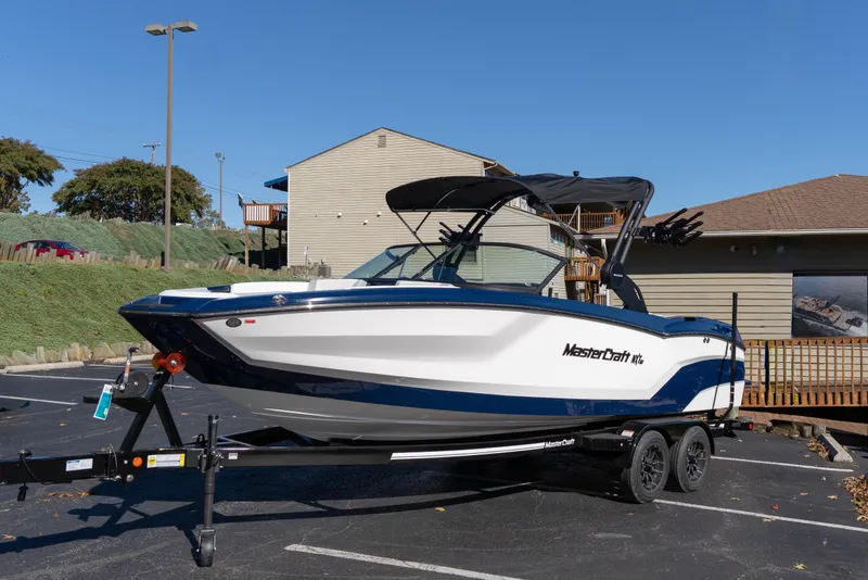 The Image of 2026 MasterCraft NXT23 boat on trailer in parking lot, sunny day. - 0