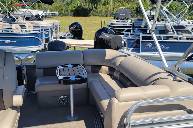 Slide: The Image of 2023 Sun Tracker Party Barge 20 DLX with beige seating and table, docked outdoors. - 6