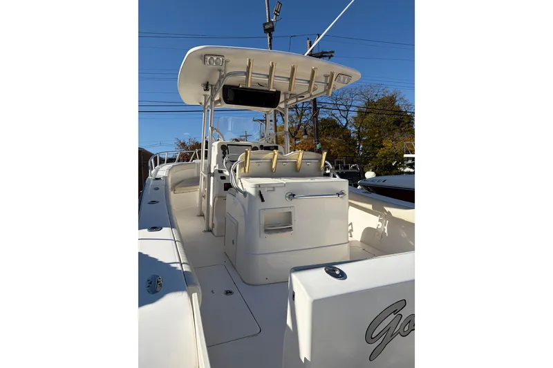 Slide: The Image of 2006 Mako 284 Center Console boat with T-top and seating, docked under clear sky. - 4