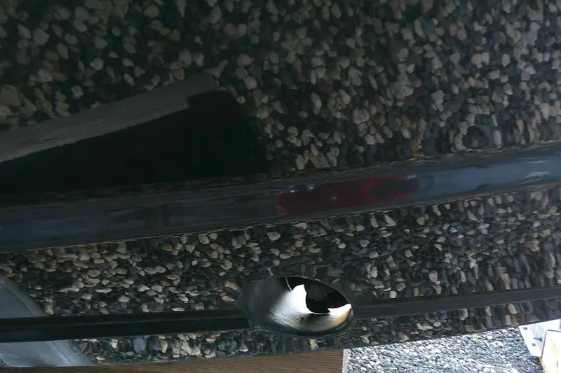 Slide: The Image of 2022 Regal 29 OBX boat hull with propeller, resting on gravel surface. - 11