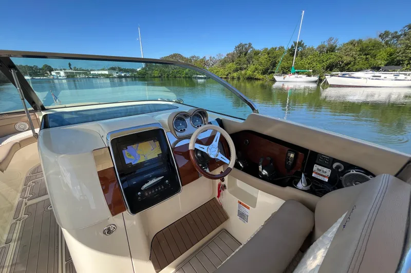 Slide: The Image of 2022 Chris-Craft Launch 35 GT I/O cockpit with navigation display, steering wheel, and serene water view. - 19