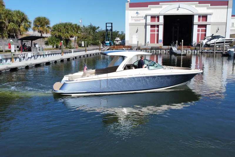 Slide: The Image of 2022 Chris-Craft Launch 35 GT I/O boat cruising near a marina on a sunny day. - 2