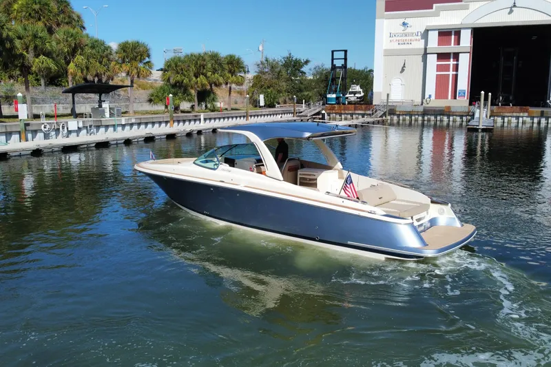 Slide: The Image of 2022 Chris-Craft Launch 35 GT I/O boat cruising near a marina with palm trees. - 3