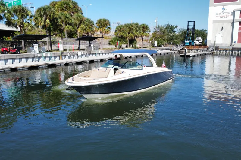 Slide: The Image of 2022 Chris-Craft Launch 35 GT I/O boat cruising near a marina with palm trees. - 5