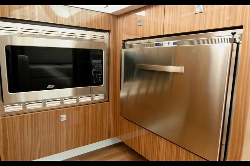 Slide: The Image of Modern kitchen appliances in 2024 Cruisers Yachts 50 Cantius, featuring microwave and stainless steel fridge. - 16