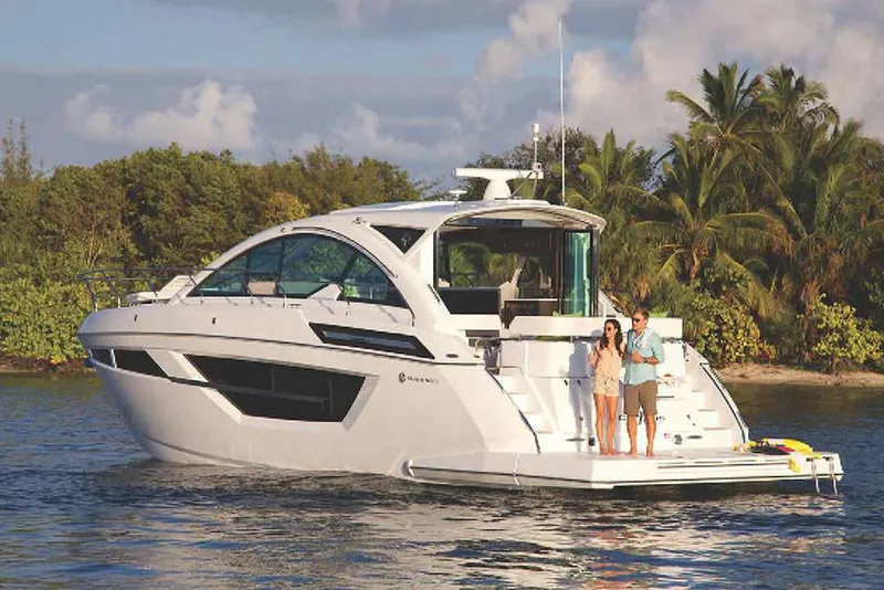 Slide: The Image of 2024 Cruisers Yachts 50 Cantius on water with two people onboard, tropical backdrop. - 4