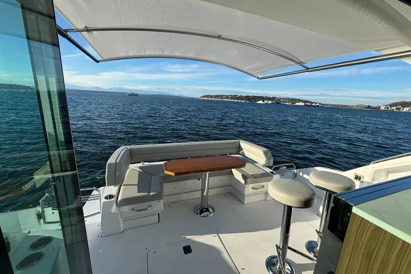 Slide: The Image of 2024 Cruisers Yachts 50 Cantius deck with seating, table, and ocean view. - 46