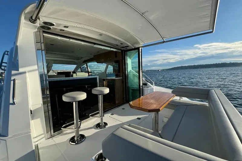 Slide: The Image of 2024 Cruisers Yachts 50 Cantius, luxurious deck view with seating and ocean backdrop. - 8