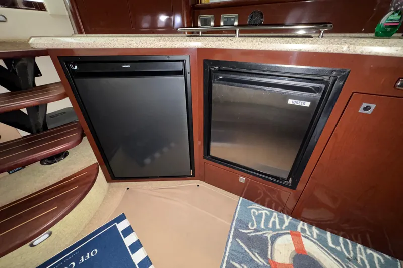 Slide: The Image of Interior of 2008 Sea Ray 40 Sundancer with dual refrigerators and wooden cabinetry. - 9