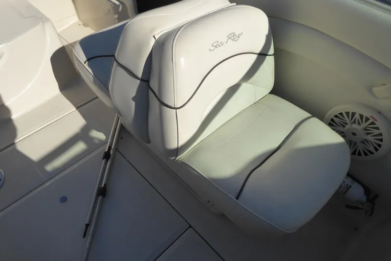Slide: The Image of 2004 Sea Ray 225 Weekender boat interior with white seating and speaker. - 24