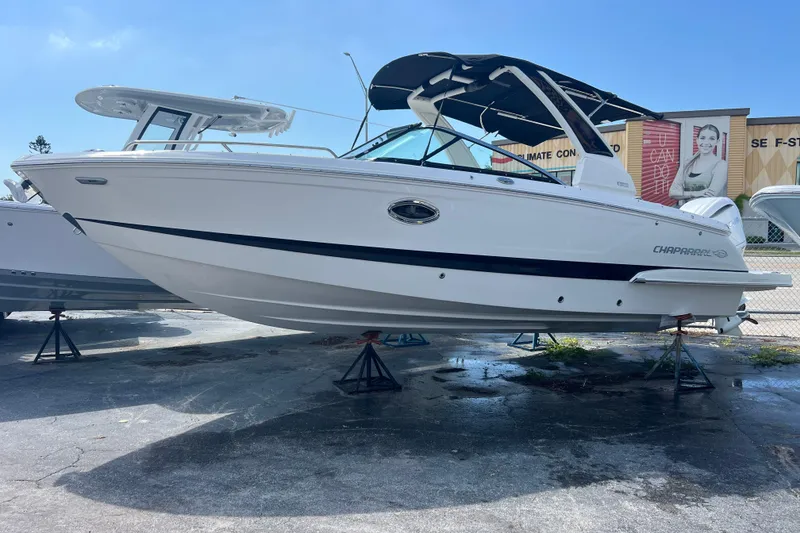 Slide: The Image of 2025 Chaparral 270 OSX boat displayed on stands under clear blue sky. - 2