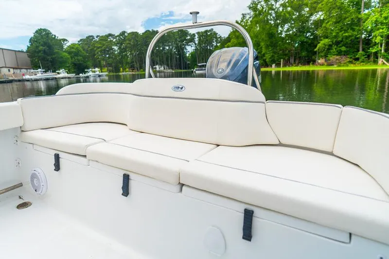 Slide: The Image of 2026 Sea Hunt Ultra 229 boat interior with white seating, docked by a serene lake. - 10