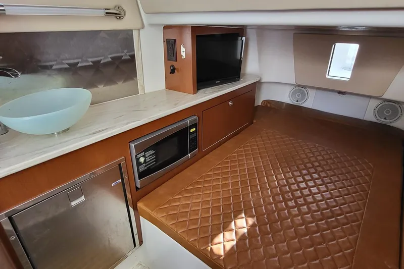 Slide: The Image of 2018 Edgewater 370CC cabin interior with bed, microwave, TV, and modern amenities. - 11