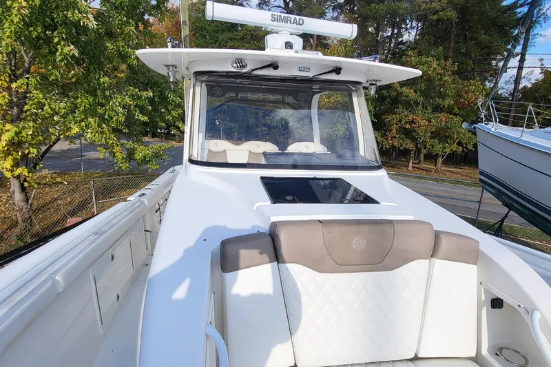 Slide: The Image of 2018 Edgewater 370CC boat with white seating and Simrad electronics, surrounded by trees. - 15