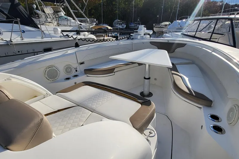 Slide: The Image of 2018 Edgewater 370CC boat interior with seating and table, docked at marina. - 16