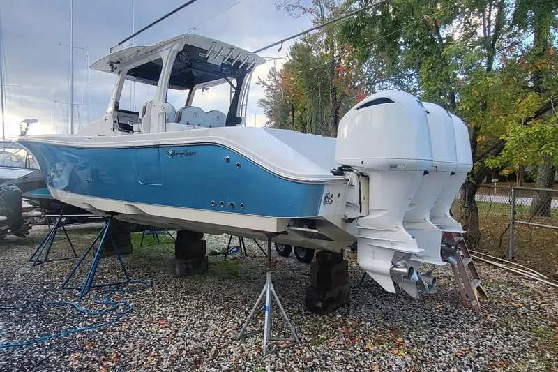 Slide: The Image of 2018 Edgewater 370CC boat with dual outboard engines on a gravel lot. - 2