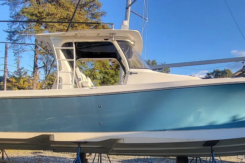 Slide: The Image of 2018 Edgewater 370CC boat with blue hull, docked outdoors under clear sky. - 3