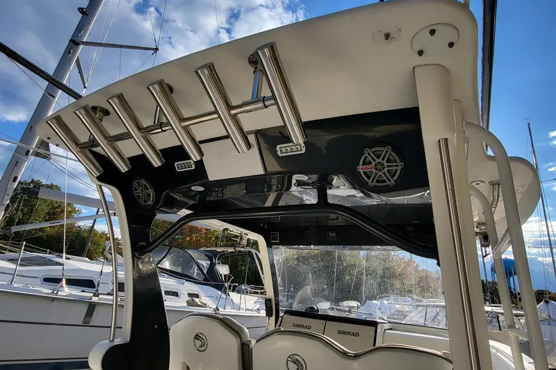 Slide: The Image of 2018 Edgewater 370CC boat interior with rod holders and speakers, docked near sailboats. - 8
