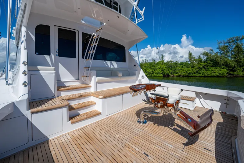 Slide: The Image of 2008 Viking 74 Enclosed Bridge yacht with teak deck and fishing chair, docked by lush greenery. - 13