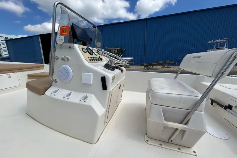 Slide: The Image of 1997 Sea Pro SV2100CC Bay Boat interior with console and seating, docked under blue sky. - 12