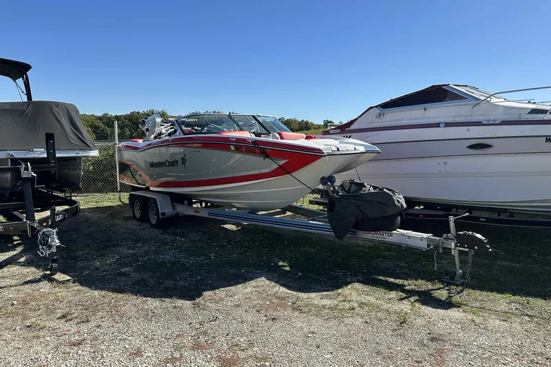 The Image of 2016 MasterCraft X23 boat on trailer, parked outdoors under clear blue sky. - 1