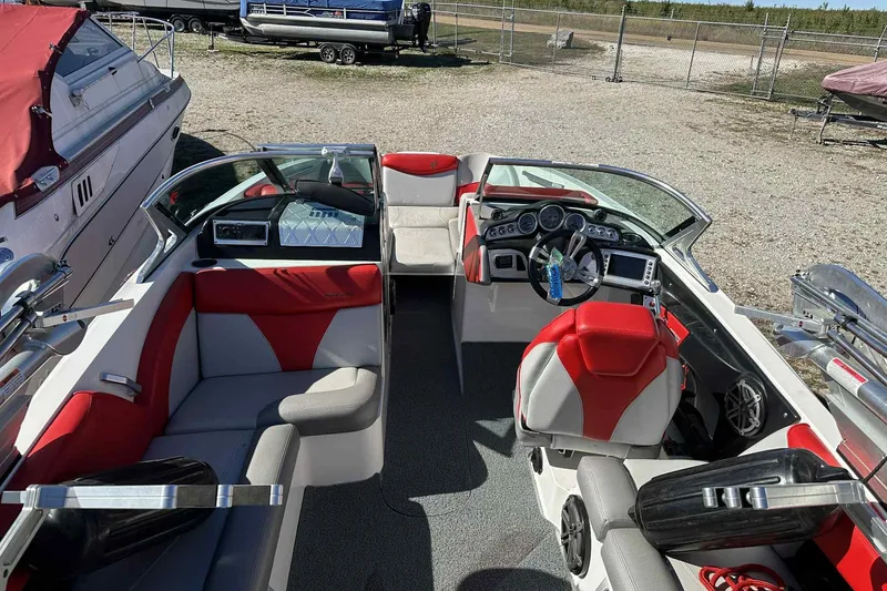 Slide: The Image of 2016 MasterCraft X23 boat interior with red and gray seating, steering wheel, and dashboard. - 13