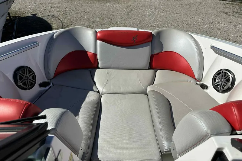 Slide: The Image of 2016 MasterCraft X23 boat interior with red and gray seating, cup holders, and speakers. - 23