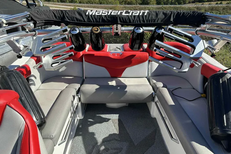 Slide: The Image of 2016 MasterCraft X23 boat interior with red and gray seating, wakeboard racks, and speakers. - 25