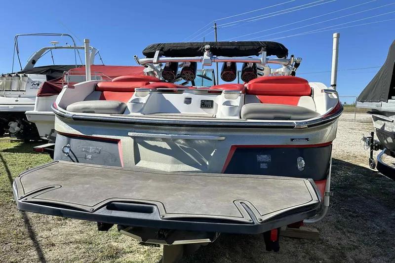 Slide: The Image of 2016 MasterCraft X23 boat with red seating and wakeboard tower, parked outdoors. - 5