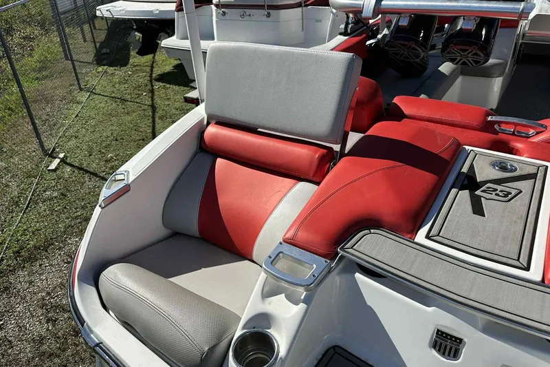 Slide: The Image of 2016 MasterCraft X23 boat interior with red and gray seating, cup holder, and speaker system. - 9
