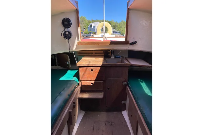 Slide: The Image of Interior of a 1969 Greenwich 24 sailboat with wooden cabinetry and green seating. - 3