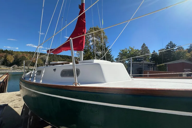 Slide: The Image of 1969 Allied Greenwich 24 sailboat docked, featuring green hull and red sail, under clear blue sky. - 8