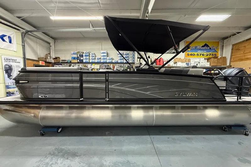 The Image of 2026 Sylvan L-3 CLZ DH pontoon boat in showroom, featuring sleek design and black canopy. - 2