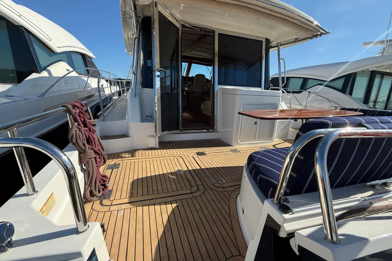 Slide: The Image of 2017 Sabre 48 Salon Express yacht deck with seating and table, docked beside other boats. - 14