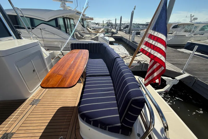 Slide: The Image of 2017 Sabre 48 Salon Express yacht with striped seating and American flag at marina. - 15