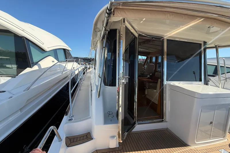 Slide: The Image of 2017 Sabre 48 Salon Express yacht with open cabin door, docked alongside another vessel. - 16