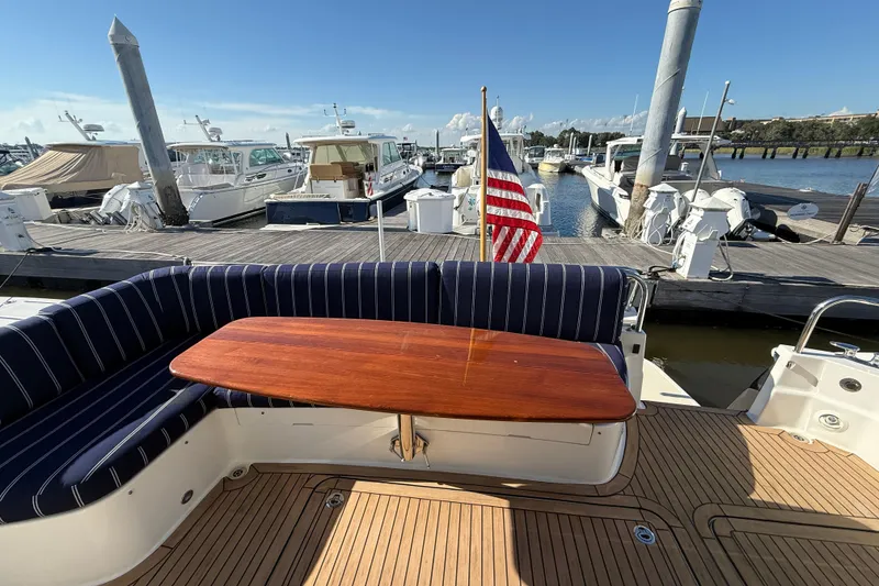 Slide: The Image of 2017 Sabre 48 Salon Express yacht with wooden table and striped seating at marina. - 18