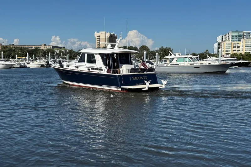 Slide: The Image of 2017 Sabre 48 Salon Express yacht cruising in a marina with other boats and buildings in the background. - 6