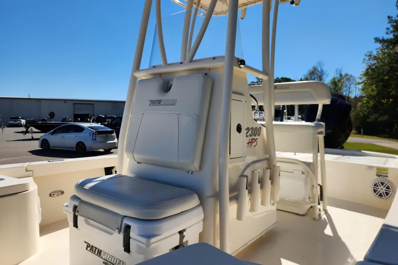 Slide: The Image of 2015 Pathfinder 2300 HPS boat interior with seating and storage, parked outdoors. - 10