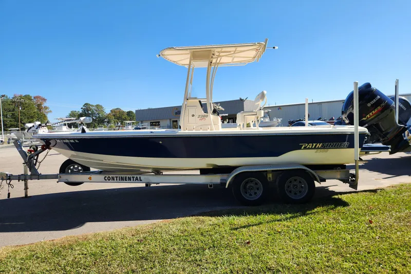 Slide: The Image of 2015 Pathfinder 2300 HPS boat on trailer, parked outdoors under clear blue sky. - 6
