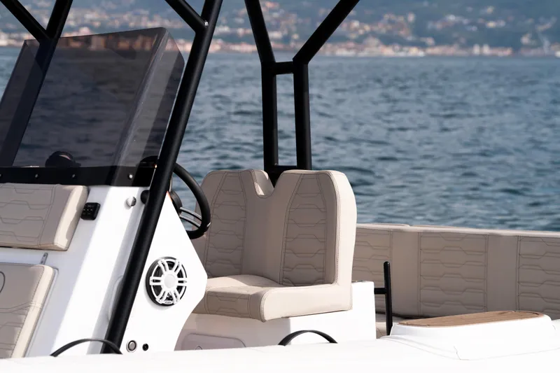 Slide: The Image of 2026 Aqvaboats Luxrib 25 interior with beige seating, steering console, and ocean backdrop. - 36
