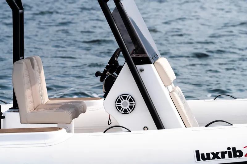 Slide: The Image of 2026 Aqvaboats Luxrib 25 boat interior with beige seating and steering console on water. - 39