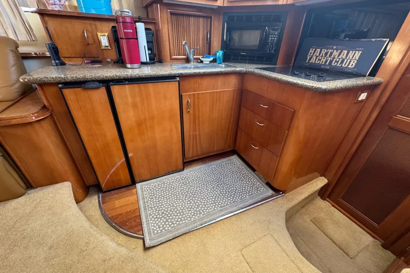 Slide: The Image of 2003 Carver 444 Cockpit Motor Yacht kitchen with wood cabinetry, granite countertops, and modern appliances. - 22