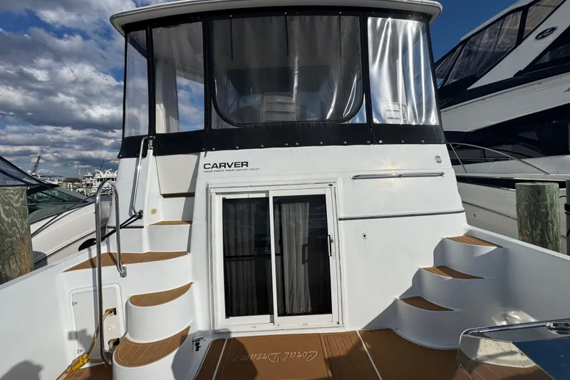 Slide: The Image of 2003 Carver 444 Cockpit Motor Yacht with white exterior and wooden steps, docked at marina. - 6