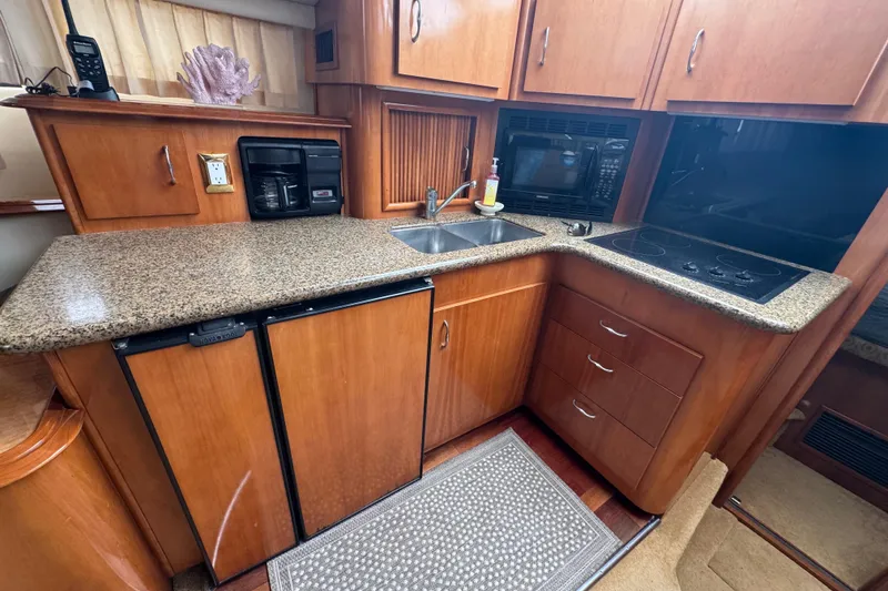 Slide: The Image of 2003 Carver 444 Cockpit Motor Yacht kitchen with granite countertops, sink, stove, and microwave. - 30