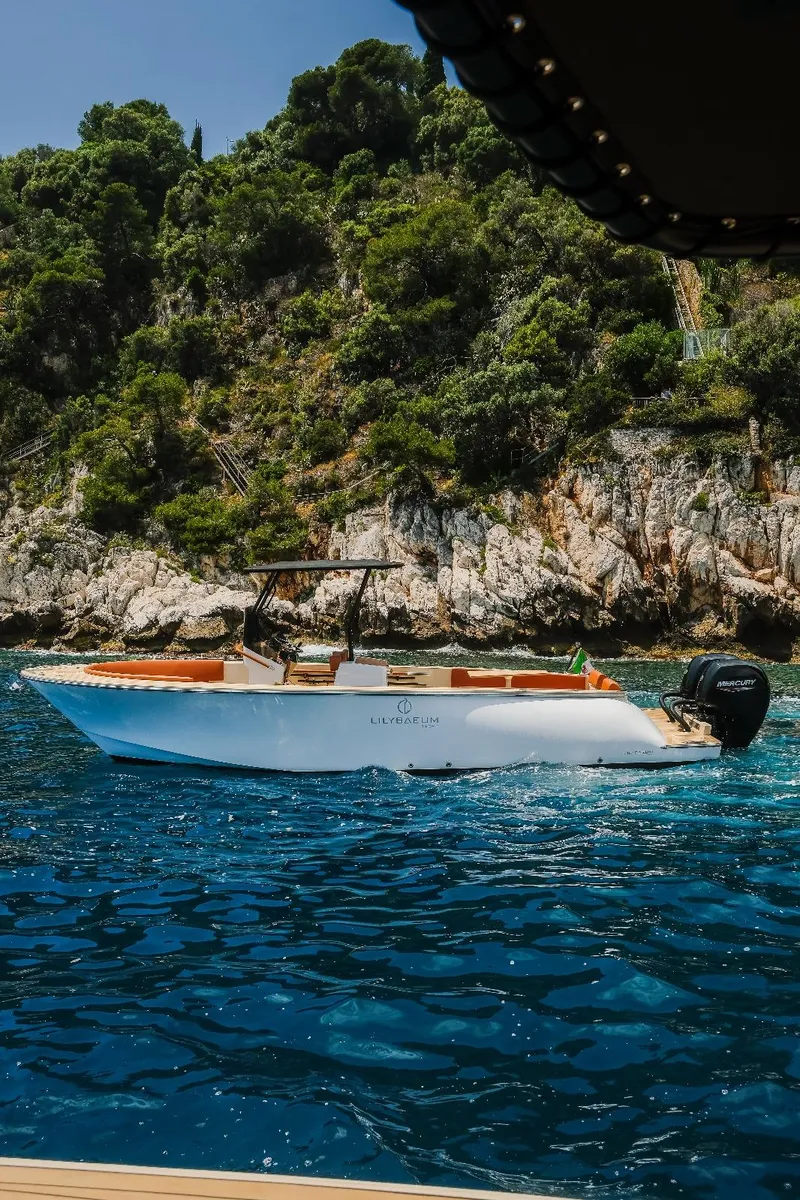 Slide: The Image of Lilybaeum Levanzo 25 Lounge Deck boat cruising near rocky coastline, 2025 model. - 0