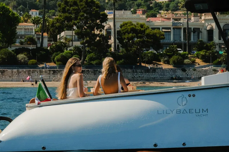 Slide: The Image of Two people relaxing on a 2025 Lilybaeum Levanzo 25 Lounge Deck yacht near a scenic coastline. - 10