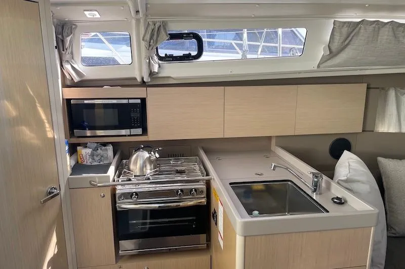 Slide: The Image of Interior of 2022 Beneteau Oceanis 35.1 yacht kitchen with stove, sink, and microwave. - 4