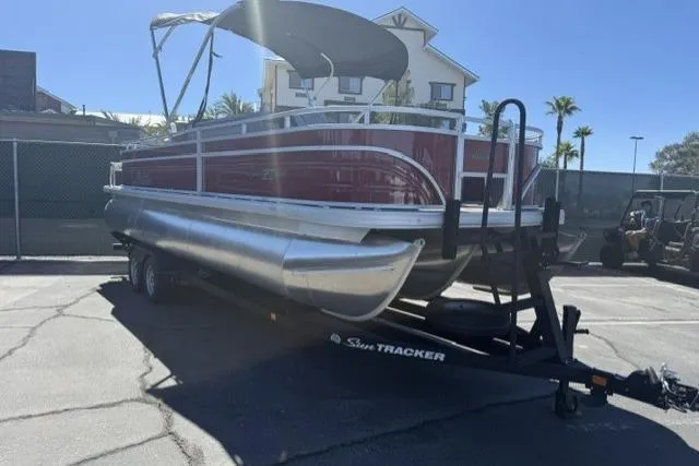 Slide: The Image of 2026 Sun Tracker Sportfish 24 XP3 pontoon boat on trailer, parked outdoors. - 1